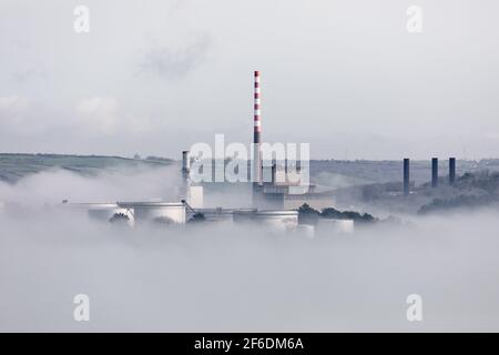 Ahada, Cork, Irland. 31st. März 2021.die Morgensonne beginnt, den Meeresnebel zu entkeichen, der die Lagertanks der Ölraffinerie und des Elektrizitätswerks in Ahada, Co. Cork, Irland, umgibt. - Credit; David Creedon / Alamy Live News Stockfoto