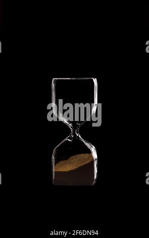Eine Sanduhr, moderne Sanduhr, die die verlaufende Zeit in einem Countdown bis zu einem Stichtag misst, auf schwarzem isolierten Hintergrund mit Kopierraum. Stockfoto