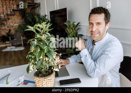 Ein selbstbewusster, gutaussehender Geschäftsmann verwendet einen Laptop, der im Heimbüro an Projekten oder Finanzberichten arbeitet. Erfolgreiche stilvolle männliche Freiberufler ist Stockfoto