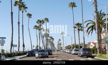 Oceanside, California USA - 16 Feb 2020: Autos auf der Straße und Menschen zu Fuß, Uferpromenade. Tropischer Strand am Pazifischen Ozean, Touristenresort mit Palmen Stockfoto