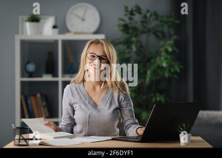 Glückliche Blondine, die zu Hause studiert Stockfoto