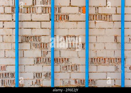 Textur von grauen Ziegel gemalten Wand und vier blaue Rohre, industriellen Hintergrund Stockfoto