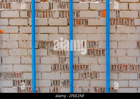 Textur von grauen Ziegel gemalten Wand und drei blaue Rohre, industriellen Hintergrund Stockfoto