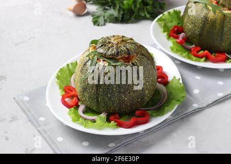 Gebackene Zucchini gefüllt mit Reis und Gemüse auf einem Teller auf hellgrauem Hintergrund. Vegetarisches Essen. Stockfoto