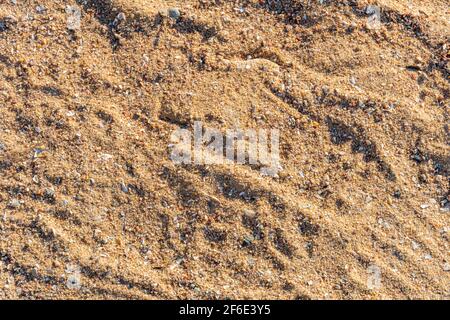 Sandstruktur am Strand bei Sonnenuntergang, Sandhintergrund, unebenes Sandmuster Stockfoto