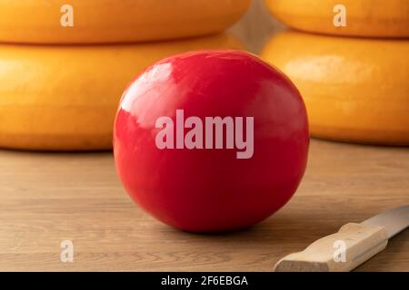 Ganze holländische rote Edam Käse auf einem Schneidebrett und Große Käsesorten im Hintergrund Stockfoto