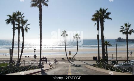 Oceanside, California USA - 8 Feb 2020: Menschen, die spazieren gehen, Uferstraße des Resorts, tropischer Pazifikstrand mit Palmen. Person ridin Stockfoto