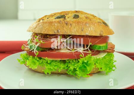 Ein Sandwich mit Speck und frischem Gemüse. Appetitliches Sandwich auf hellem Hintergrund mit Platz für Text Stockfoto