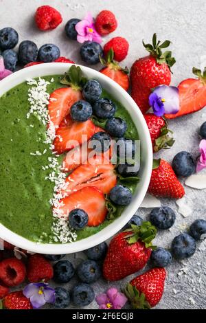 Matcha Grüner Tee Frühstück Superfoods Smoothies Schüssel mit Erdbeeren, Heidelbeeren, Kokosflocken obendrauf, Draufsicht, flach legen Stockfoto