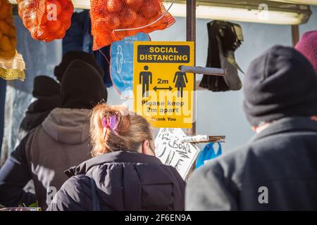 London, UK - 5 February, 2021 - Social Distancing Zeichen an einem Outdoor-Produkte Stand auf Wood Green High Street angezeigt Stockfoto