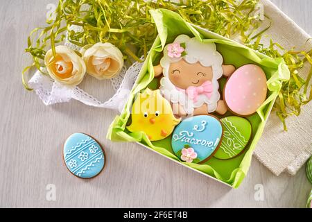 Draufsicht auf bunte osterlebkuchen mit leckerer Glasur in der Geschenk-Box. Leckere Kekse in unterschiedlicher Form und Größe. Isoliert über Holz Stockfoto