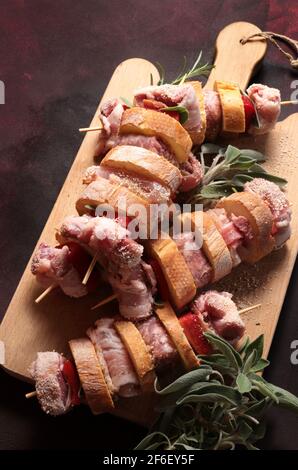 Rustikale rohe Spieße, fertig zum Kochen, mit truthahn, Wurst, Schweinefleisch, Gemüse, Kräuter und Brotscheiben auf Holzbrett. Nahaufnahme. Direkt darüber. Stockfoto