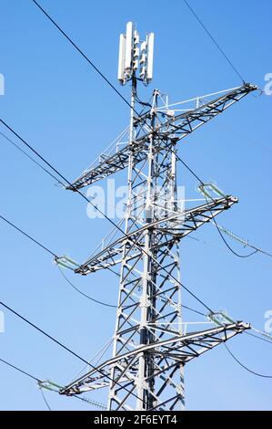 Strommast für den Transport von Elektrizität mit einer Antenne an Top mit einem klaren blauen Himmel Stockfoto