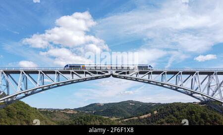 Blick auf eine Brücke ( Viaduc ) mit einem Zug, der an ihr vorbeifährt in Aveyron , Frankreich Stockfoto