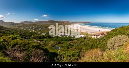 Panoramablick auf Noordhoek Long Beach mit weißem Sand in der Nähe von Kapstadt, Südafrika gegen blauen Himmel. Vom Chapmans Peak Drive aus gesehen. Die Stadt Kommet Stockfoto