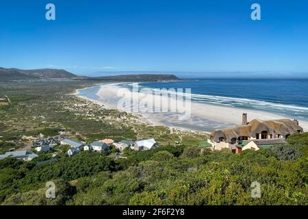 Panoramablick auf Noordhoek Long Beach mit weißem Sand in der Nähe von Kapstadt, Südafrika gegen blauen Himmel. Vom Chapmans Peak Drive aus gesehen. Die Stadt Kommet Stockfoto