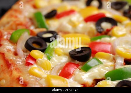 Pizza Farmers Pizza, hergestellt aus rotem, grünem und gelbem Paprika, Zwiebeln, schwarzen Oliven, Kegel und Mozzarella-Käse, dünne Gebäckkruste auf einem schwarzen gelegt Stockfoto