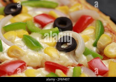 Pizza Farmers Pizza, hergestellt aus rotem, grünem und gelbem Paprika, Zwiebeln, schwarzen Oliven, Kegel und Mozzarella-Käse, dünne Gebäckkruste auf einem schwarzen gelegt Stockfoto