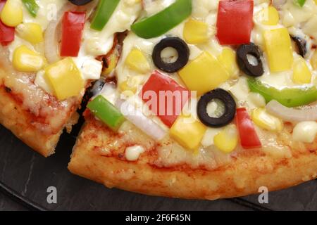 Pizza Farmers Pizza, hergestellt aus rotem, grünem und gelbem Paprika, Zwiebeln, schwarzen Oliven, Kegel und Mozzarella-Käse, dünne Gebäckkruste auf einem schwarzen gelegt Stockfoto