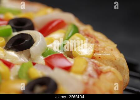 Pizza Farmers Pizza, hergestellt aus rotem, grünem und gelbem Paprika, Zwiebeln, schwarzen Oliven, Kegel und Mozzarella-Käse, dünne Gebäckkruste auf einem schwarzen gelegt Stockfoto