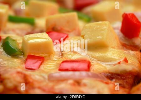 Pizza Paneer Makhani, hausgemachte leckere Pizza aus rotem und grünem Paprika, Zwiebeln, Paneer und Mozzarella-Käse, dünne Gebäckkruste platziert Stockfoto