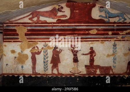 Etruskische Entertainer: Ein männlicher Jongleur, eine akrobatin und ein Musiker, der zwei Flöten spielt. Wandmalerei in einem 2.500 Jahre alten etruskischen Grab, dem Jugglergrab oder Tomba dei Giocolieri, in der Nekropole Monterozzi der antiken Stadt Tarchuna oder Tarchna, heute Tarquinia, Latium, Italien. Der Jongleur hält zwei Scheiben, während er vor zwei Körben steht, während die akrobatin einen schwer aussehenden Kerzenleuchter auf ihrem Kopf ausbalanciert. Stockfoto