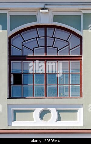 Rechteckiges Bogenfenster mit braunem Rahmen an einer grauen Wand. Aus einer Reihe von Fenstern von St. Petersburg. Stockfoto