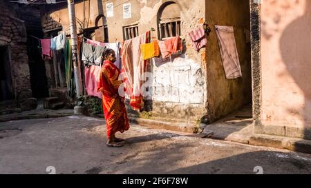 Kalkutta, Westbengalen, Indien - 2018. Januar: Eine indische Frau, die einen bunten Sari trägt, steht vor den rustikalen Wänden eines Hauses auf den Straßen der Stockfoto