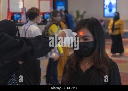 Pekanbaru, Riau, Indonesien. März 2021, 31st. Ein Offizier überprüft die Körpertemperatur einer Frau, bevor sie das Cinepolis-Kino betritt, nachdem die Einschränkungen des Coronavirus in Pekanbaru, Indonesien, einfach waren. Pekanbaru Kino wiedereröffnet, nachdem sie für ein Jahr geschlossen. Quelle: Afrianto Silalahi/ZUMA Wire/Alamy Live News Stockfoto