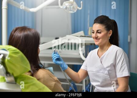 Zahnärztin lächelt während der Arbeit mit dem Patienten Stockfoto