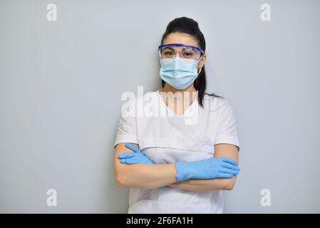 Nette Frau Zahnarzt in Uniform, Schutzbrille und Gesichtsmaske Stockfoto
