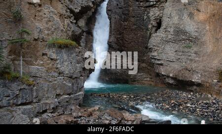 Die Upper Falls am Johnston Canyon in Banff, Alberta, Kanada, ragen hinter einer großen Felswand hervor. Stockfoto