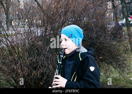 Dnepropetrovsk, Ukraine - 03.29.2021: Ein Junge im Park spielt Klarinette. Das Kind ist gut gelaunt. Stockfoto