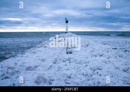 Ein Pfad aus Schnee und Eis führt den Pier hinauf zum Grand Bend Lighthouse am Grand Bend Beach im Januar 2021, Lambton Shores. Stockfoto