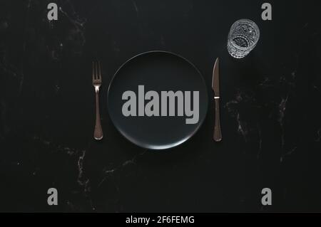 Nachbau eines leeren luxuriösen Tellers gegen dunklen Marmor Stockfoto