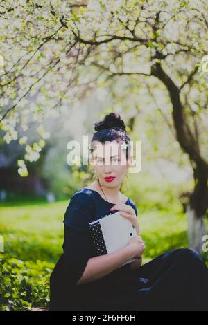 Glückliche Frau sitzt im Frühling Kirschgarten Stockfoto