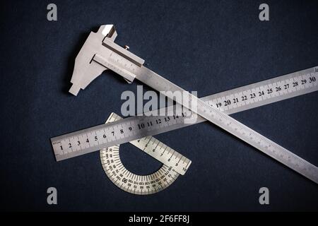 Goniometer und Lineal und Messschieber drei Typen auf dunkelgrau-schwarzem Hintergrund. Schwarzweißfotos ohne Farbe und Schwarzweiß. Stockfoto