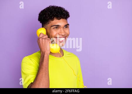 Foto-Porträt von jungen lockigen Kerl reden am Telefon suchen Copyspace hält Festnetz isoliert auf pastellviolettem Hintergrund Stockfoto