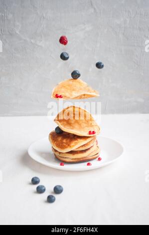 Fliegende frisch gekochte Pfannkuchen und Beeren mit Honig, Walnuss zum Frühstück. Stockfoto