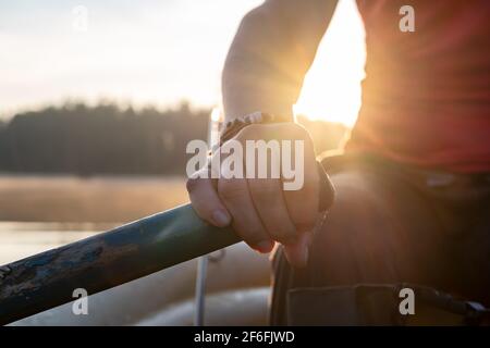 Weibliche Hände halten ein Paddel in einem aufblasbaren Boot, vor dem Hintergrund eines Sees im Nebel, Sonnenaufgang und Wald. Stockfoto