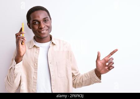 Afro Male In Casual Wear Talking On Phone With Friend Sharing News, Lächelnd Und Zeigenden Finger Auf Der Seite, Isoliert Weißen Hintergrund Stockfoto
