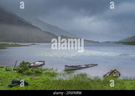 Zwei versunkene Boote im Lough Gummeenduff, atmosphärischer, dramatischer Sturmhimmel und Wolken, Nebel und starker Regen in Blackvalley, Rink of Kerry, Irland Stockfoto