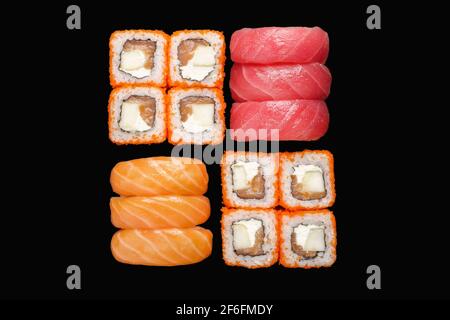 Sushi-Rollen-Set mit kalifornischem Brötchen, Nigiri-Lachs, Nigiri-Thunfisch. Isoliert auf schwarzem Hintergrund Stockfoto