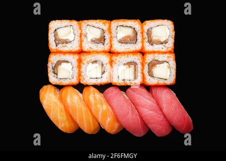 Sushi-Brötchen mit Lachs, Philadelphia-Käse, Masago-Kaviar, Apfel. Nigiri-Lachs, Nigiri-Thunfisch. Isoliert auf schwarzem Hintergrund Stockfoto