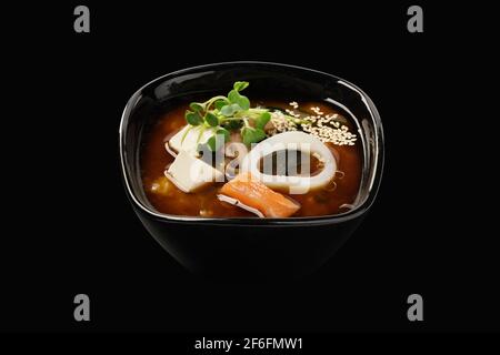 Miso-Suppe mit Lachs und Tintenfisch, Brühe, Wakame-Algen, Shiitake-Pilze, Tofu-Käse, Grüne Zwiebeln, Lauch, Sesamsamen. Japanisches Essen. Isoliert ein Stockfoto