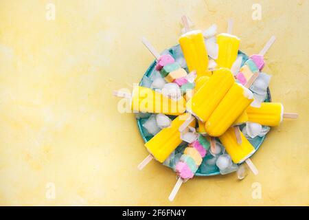 Fruchtige Fruchtknöchel. Vegan verschiedene bunte Eislollies auf einem Teller. Draufsicht, Leerraum Stockfoto