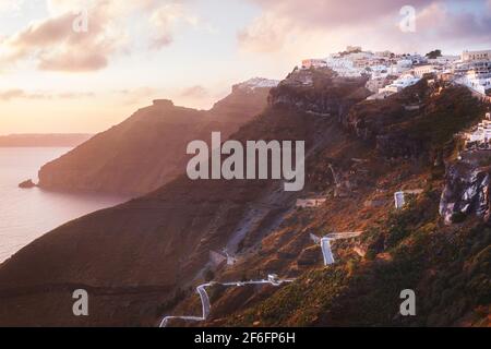 Sonnenuntergang auf der griechischen Insel Santorini, mit bunten warmes Licht und Wolken über der Stadt. Der Blick folgt dem Rand der Caldera von Thira, Skaro Stockfoto