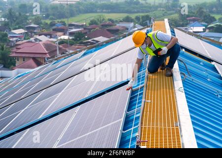 Solarenergie, asiatische Ingenieursarbeiten auf dem Dach des Solarkraftwerks, Betrieb und Wartung im Solarkraftwerk Stockfoto