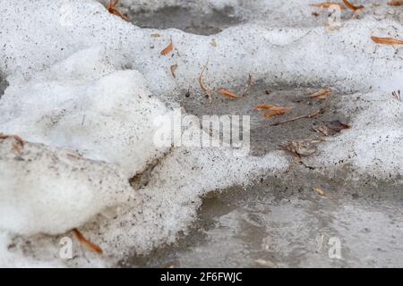 Früher Frühling schmutziger grauer geschmolzener Schnee mit Sandmuster Textur Stockfoto