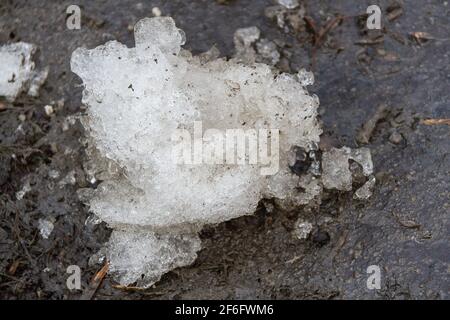 Früher Frühling schmutziger grauer geschmolzener Schnee mit Sandmuster Textur Stockfoto